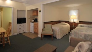 Une chambre d’hôtel avec deux lits, un bureau, une chaise, une télévision et une kitchenette.