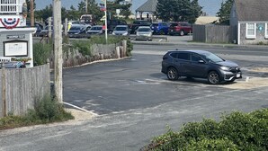 Un parking rempli de voitures, un kiosque et une vue sur la mer.