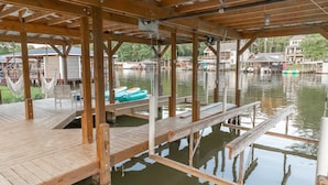 Une jetée en bois s’étendant au-dessus d’une étendue d’eau calme, avec un espace de repos abrité et une rangée de bateaux.