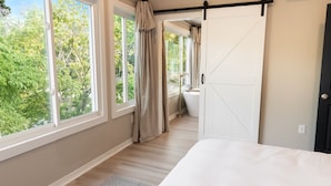 Une chambre dotée d’une grande fenêtre, d’une porte coulissante et donnant sur un balcon.