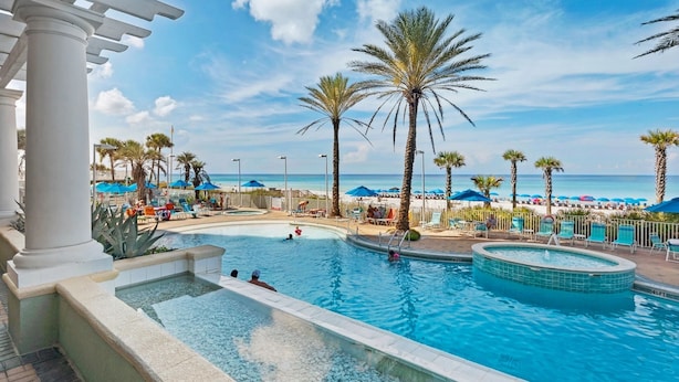 A pool area with palm trees, lounge chairs, and umbrellas. - 🏖️XL Balcony with Awesome View - 2BR Boardwalk 209C🏖️ (Panama City Beach)