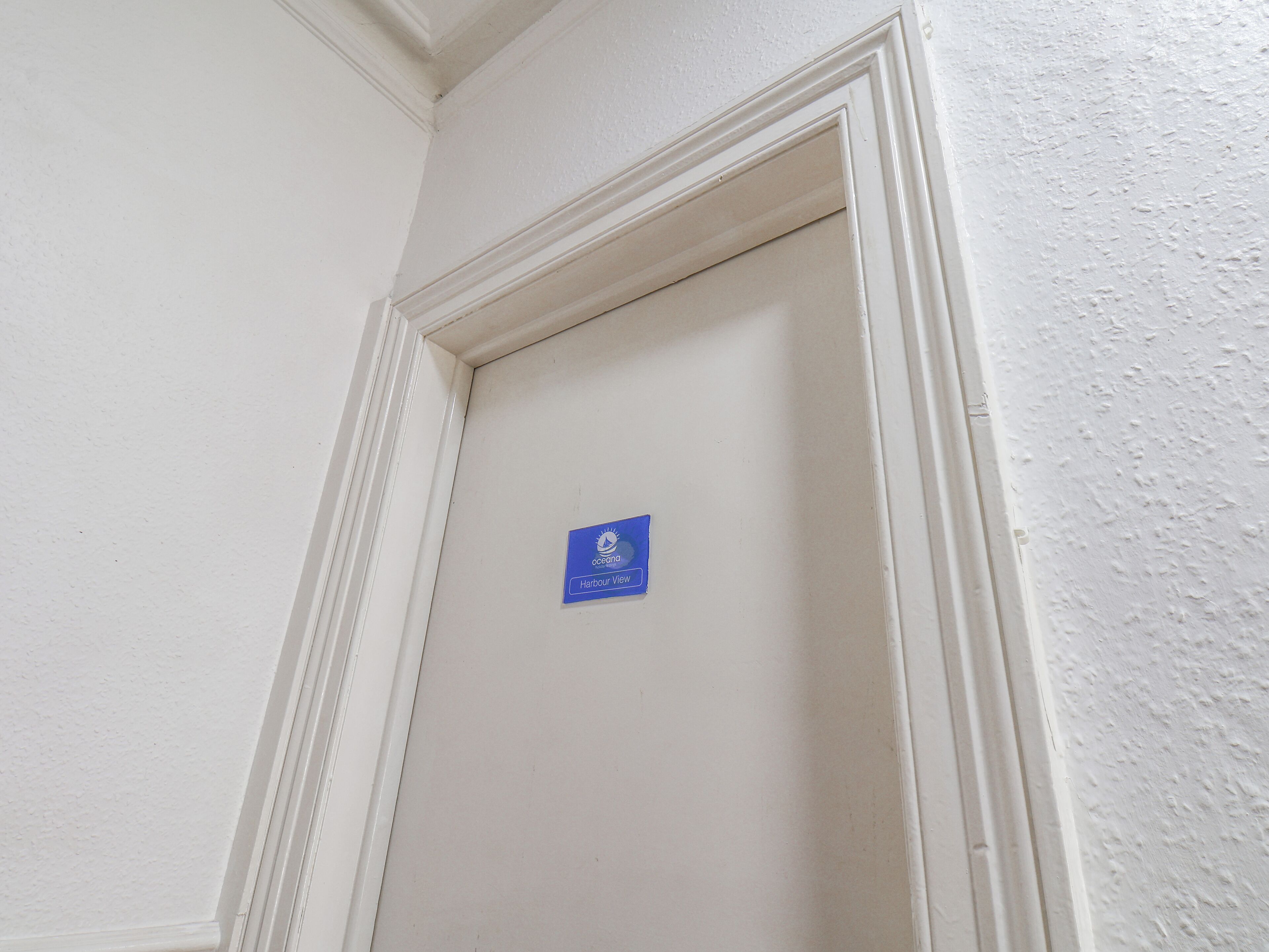 Una puerta blanca con un letrero azul que dice "Oceania Harbour View".