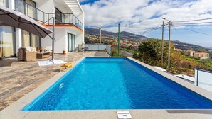Un espace piscine moderne offrant une vue dégagée sur le paysage environnant et un bâtiment doté de balcons.