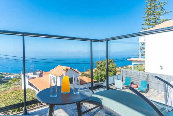 A balcony with a table, two glasses, and a pitcher of orange juice.