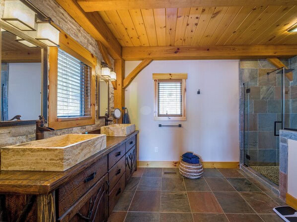 A bathroom with a stone sink, wooden vanity, a large mirror, and a glass shower enclosure. - Spacious Finger Lakes Waterfront Lodge (Road Burdett)