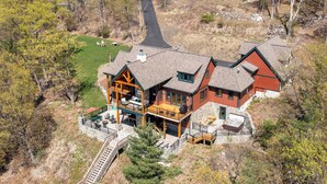 A large, multi-story lodge with a stone facade, multiple balconies, and a central patio area. - Spacious Finger Lakes Waterfront Lodge (Road Burdett)