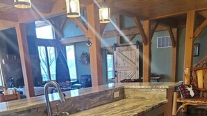 A kitchen with wooden cabinets, a marble countertop, and a stainless steel sink. - Spacious Finger Lakes Waterfront Lodge (Road Burdett)