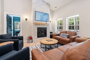 A living room with a fireplace, a large window, and a stone wall.