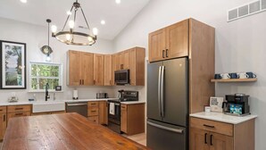 Une cuisine moderne avec des meubles en bois, un réfrigérateur en acier inoxydable, un four à micro-ondes encastré et une table à manger en bois.