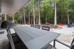 An outdoor dining area with a table and chairs, surrounded by trees. - Relax at Newly Constructed home in Egg Harbor (Egg Harbor)