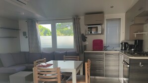 Een ruimtelijk ingerichte leefruimte met een eethoek, kitchenette en een zithoek.