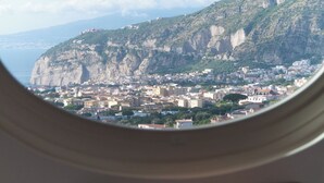 A view through a circular window of a coastal town with buildings and cliffs. - Gargiulo Resort (Sant'Agnello)