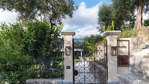 A gated entrance with a metal gate, a stone wall, and a sign that reads "rooms". - Gargiulo Resort (Sant'Agnello)