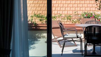 A poolside area with a glass door, outdoor seating, and a tiled wall.