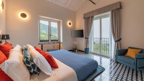 A hotel room with a bed, a sofa, a TV, a balcony with curtains, and a view of the outdoors. - Gargiulo Resort (Sant'Agnello)