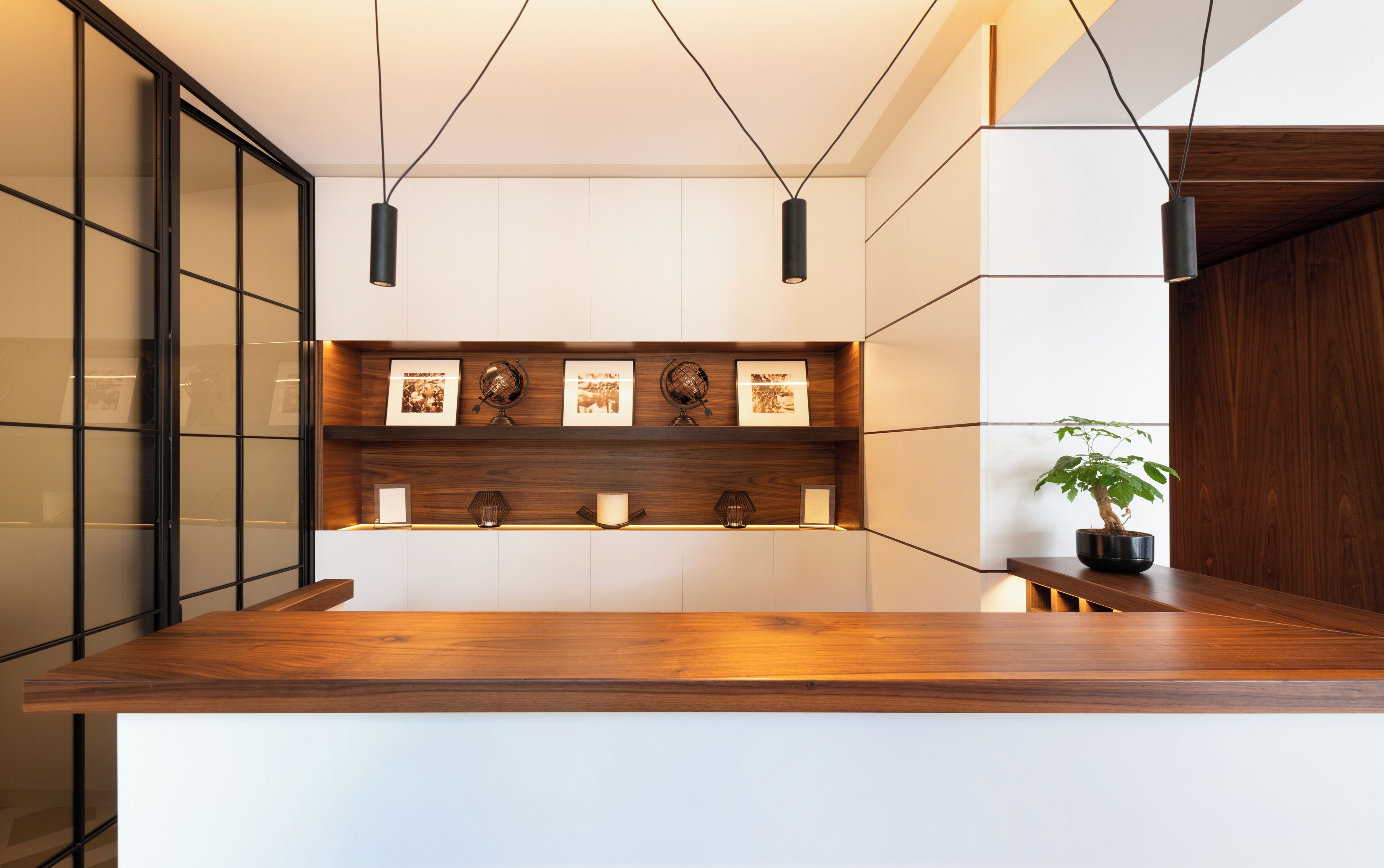 A reception desk with a wooden finish, a globe, framed photos, and a potted plant.