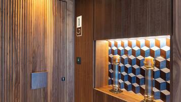 An elevator interior with a wooden finish, a number 1 sign, and a geometric patterned wall.