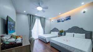 Una habitación de hotel con dos camas, un escritorio con televisor y un ventilador de techo.