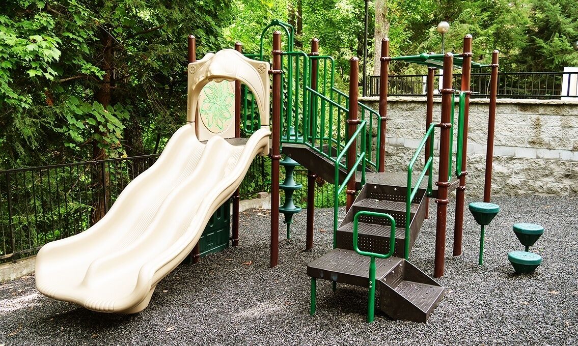Ein Spielplatz mit Rutsche, Klettergerüsten und einer kleinen Sitzgelegenheit.