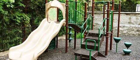 Ein Spielplatz mit Rutsche, Klettergerüsten und einer kleinen Sitzgelegenheit.
