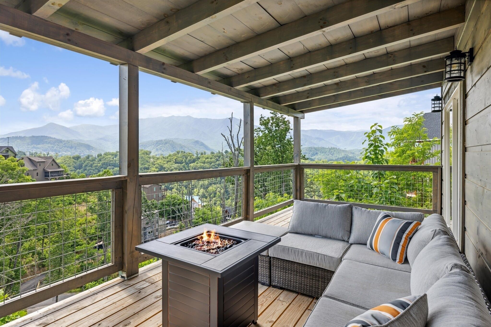 A covered outdoor seating area with a fire feature, overlooking a mountainous landscape.