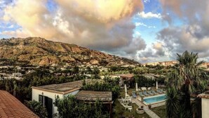 A residential area with a mountain in the background, a swimming pool, and several houses with red-tiled roofs. - Case Vacanze Le Buganville (Forio)
