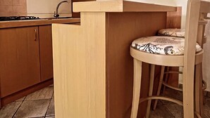A kitchen with wooden cabinets, a sink, and a chair with a patterned cushion. - Case Vacanze Le Buganville (Forio)