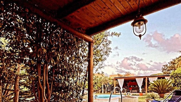 A covered outdoor area with a pool, lounge chairs, and a wooden pergola. - Case Vacanze Le Buganville (Forio)