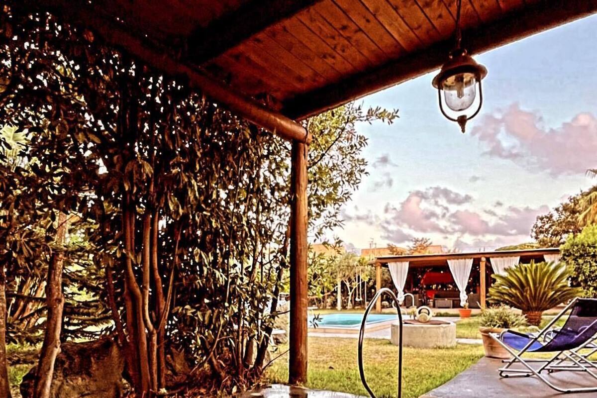 A covered outdoor area with a pool, lounge chairs, and a wooden pergola.