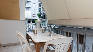 A balcony with a table and chairs, a white umbrella, and a view of buildings. - Home Away from Home 2 Bd Apt in Zografou (Zografos)