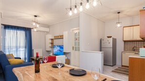 A modern apartment with a dining area, kitchen, living room, and a TV in the background. - Home Away from Home 2 Bd Apt in Zografou (Zografos)