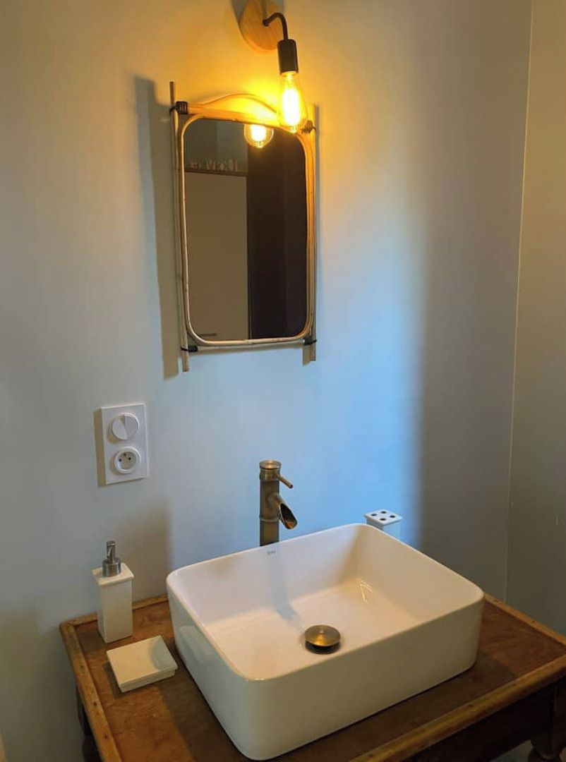 A bathroom with a white sink, a mirror, and a light fixture above the mirror.