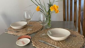 Una mesa de comedor dispuesta con dos copas de vino, dos cuencos y un florero con flores amarillas.