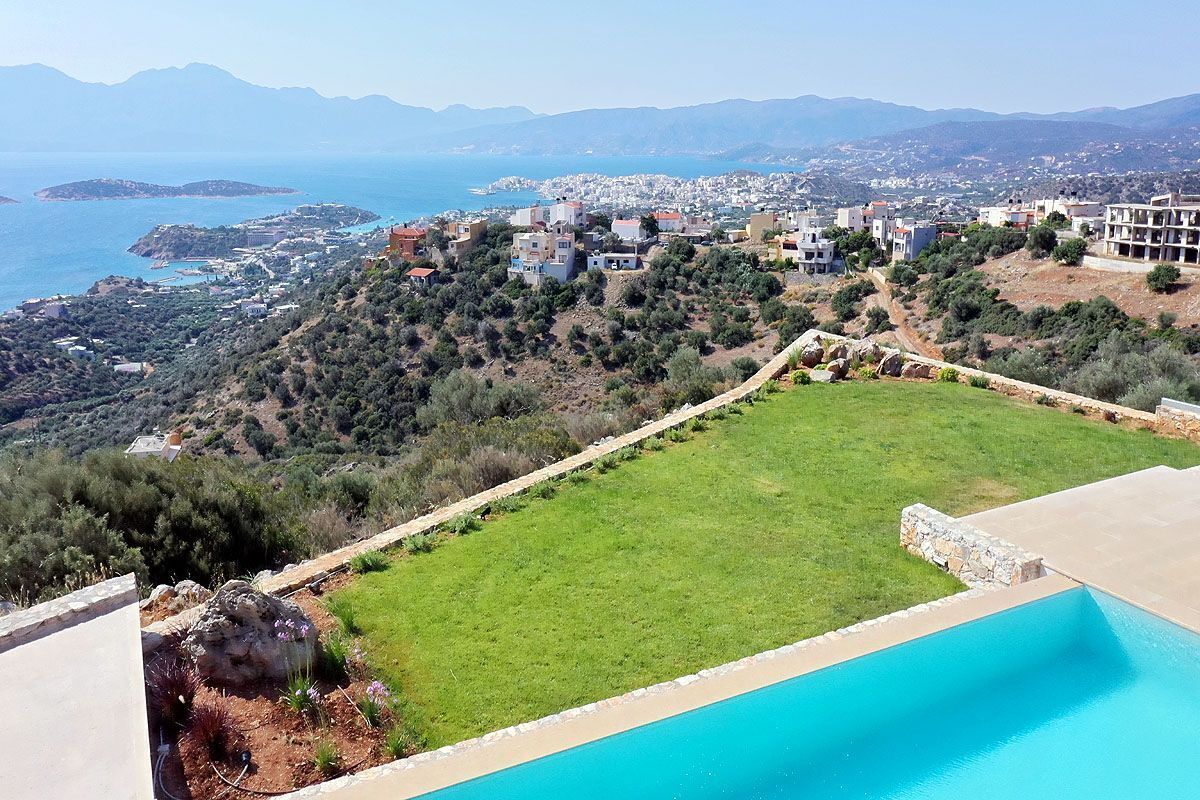 Un quartier résidentiel doté d’une piscine, de pelouses verdoyantes et offrant une vue sur la mer et les montagnes lointaines.