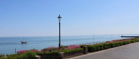 A coastal road with a street lamp, a sign reading "Bright Crescent," and a view of the sea with a boat in the distance.