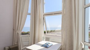 A room with a white table and chair, a radiator, and a window with curtains.