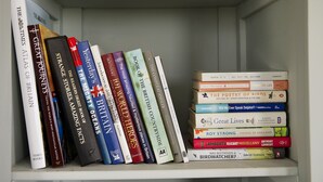 Een boekenplank met verschillende boeken, waaronder titels zoals 'The Times Atlas of Britain' en 'Strange Stories Amazing Facts'.