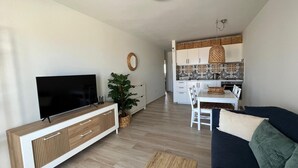 A modern living room with a flat-screen TV, a wooden cabinet, a large plant, and a dark blue sofa. - Casa Fin del Mundo El Cotillo (El Cotillo)
