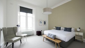 A modern bedroom with a large bed, a chair, a small table, and a nightstand. - Portrona (Isle of Lewis)