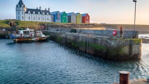 A harbor with a white building, colorful houses, and a boat. - Northstar 2 (Wick)