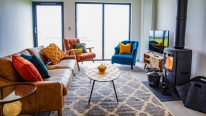 Un salon moderne avec un canapé, des fauteuils, une table, une cheminée et une grande fenêtre.