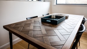 Une table à manger avec un plateau en bois à motifs chevrons, des pieds en métal noir et une pièce centrale turquoise agrémentée de saliers.