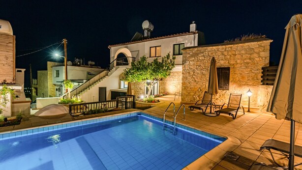 A swimming pool with a stone wall and a staircase leading to a second floor.