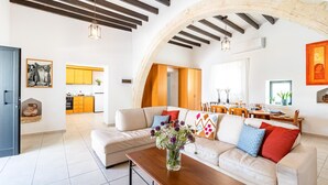 A spacious living area with a sofa, coffee table, and a dining area in the background.