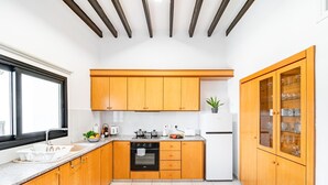 A modern kitchen with wooden cabinets, a built-in oven, a refrigerator, and a window providing natural light.