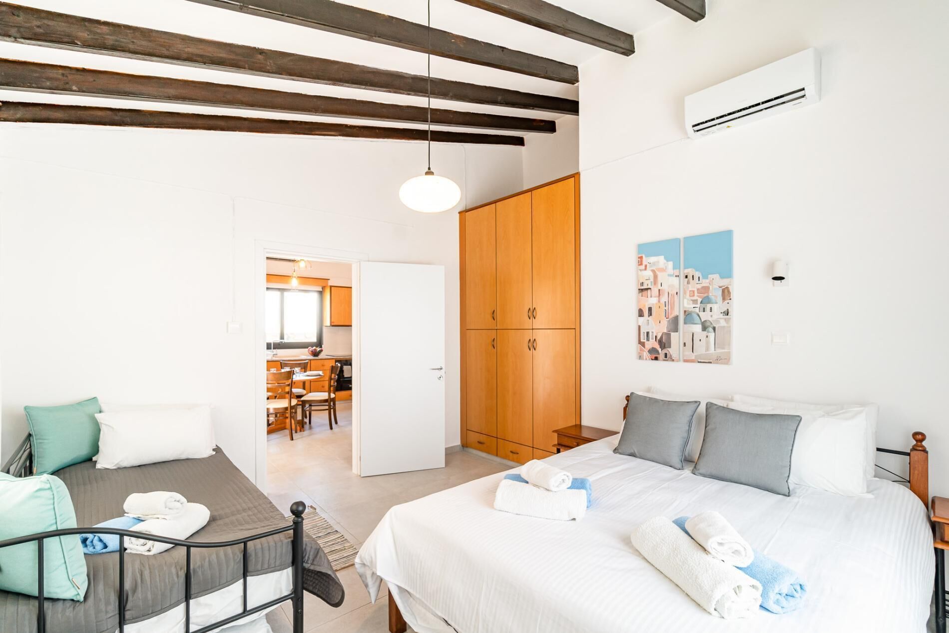 Una camera da letto con un letto, cuscini, un comodino, un armadio e un quadro appeso al muro.