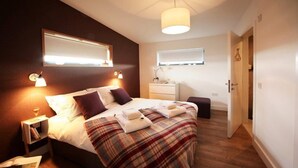 A bedroom with a bed, bedside table, nightstand, and a window. - Jog Lodge 2 - 3 Bed (Wick)