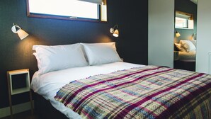 A neatly made bed with a colorful blanket, two bedside lamps, and a window above. - Jog Lodge 13 - 3 bed (Wick)