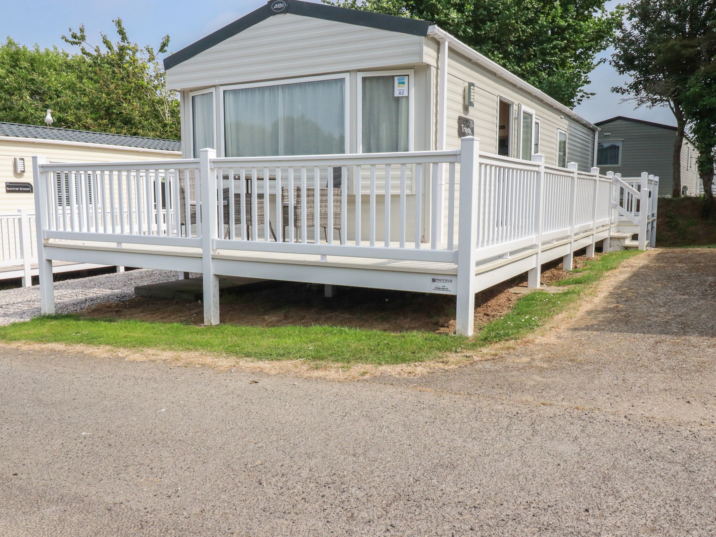 A mobile home with a white deck and a covered outdoor area.