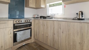Une cuisine moderne avec des meubles en bois, un four encastré, un four à micro-ondes et un grille-pain.
